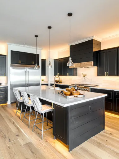 Modern kitchen with dark refinished cabinets, marble countertops, and elegant lighting, showcasing the transformation potential of cabinet refinishing by Bay Breeze Painting Company.
