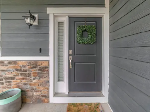 Freshly painted gray front door with a greenery wreath, surrounded by stone and gray siding in a modern entryway in Centreville, MD.