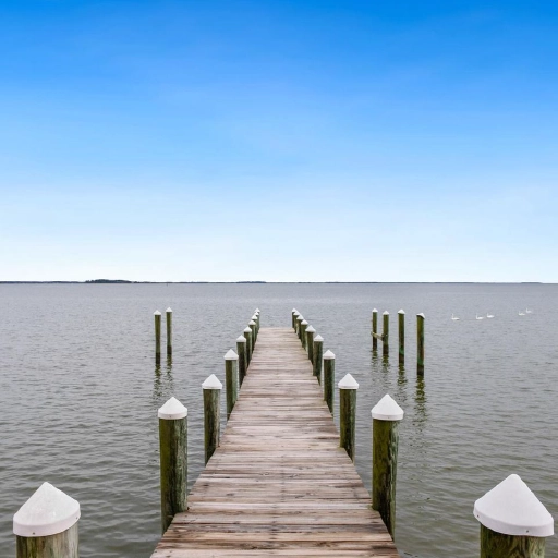 Wooden dock extending into calm waters in Chester, Maryland, with a view of the shoreline