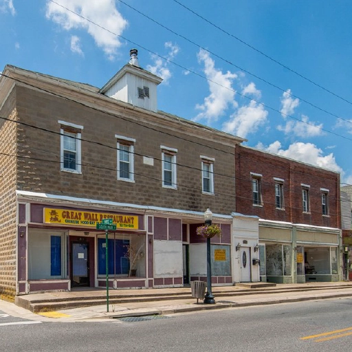 Historic commercial buildings and storefronts in downtown Federalsburg, Maryland under a bright blue sky.