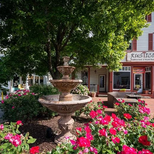 Historic downtown Stevensville, Maryland, with a tiered fountain surrounded by pink roses and a vintage storefront